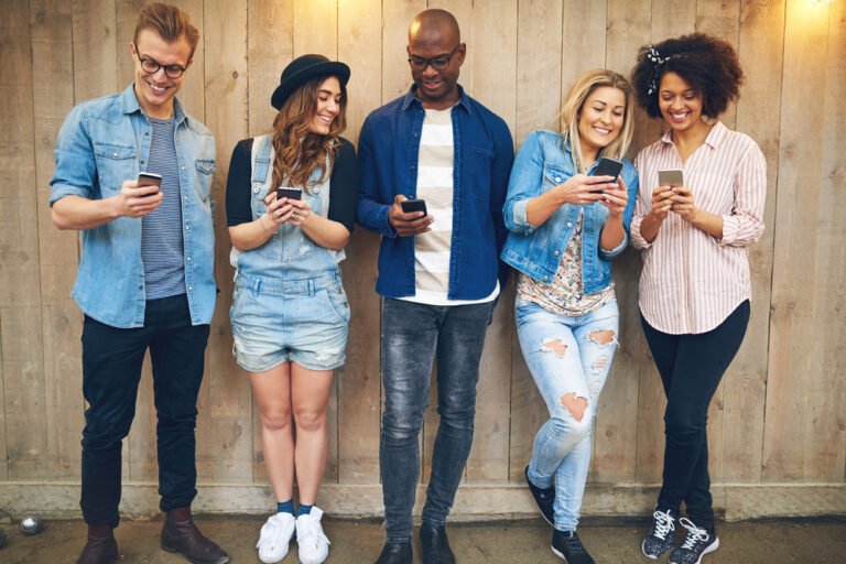 Group of 5 friends hanging out on their phones
